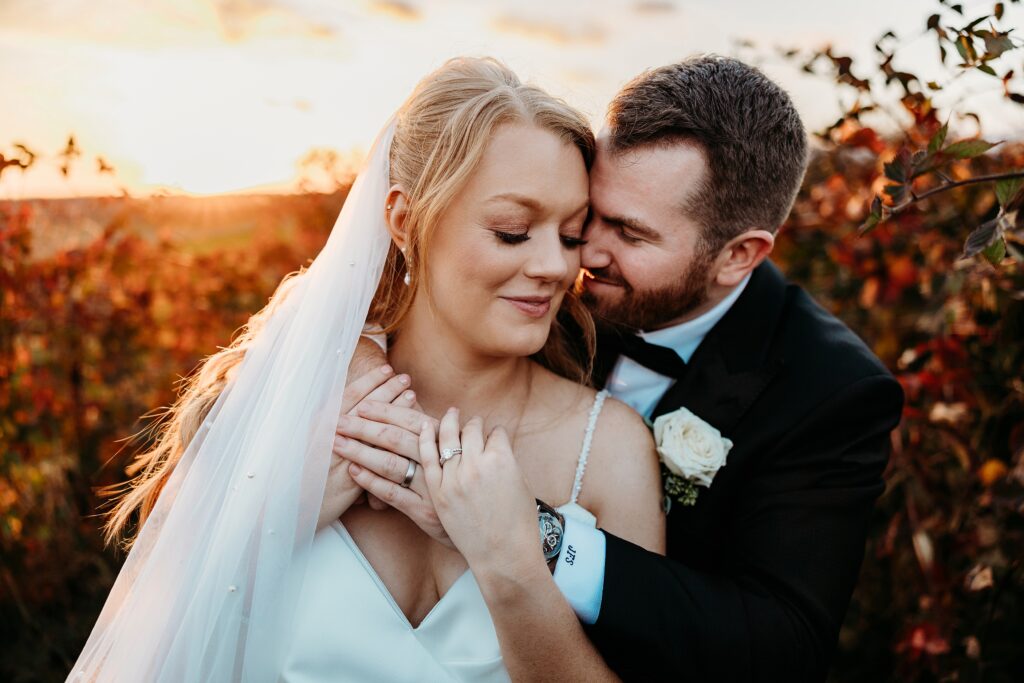 Close up of bride and groom embracing in orchard at Hubers Orchard and Winery during golden hour.
