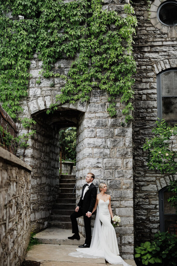 Castle & Key wedding portrait of bride and groom beside ivy covered stone walls and historic archway entrance.
