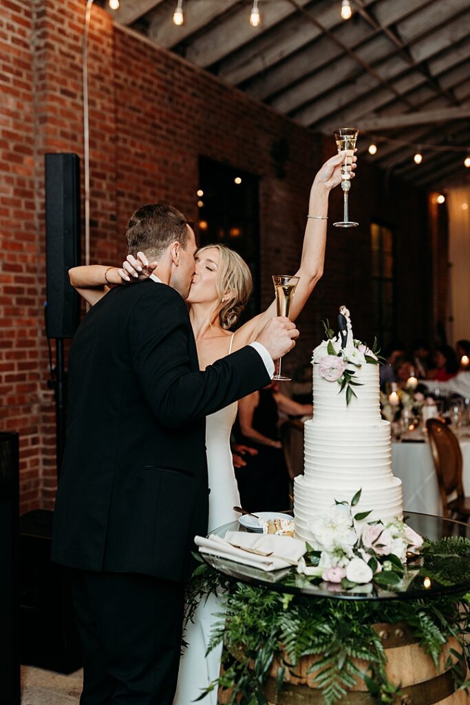 Castle & Key wedding couple sharing a kiss during the cake cutting and champagne toast at their reception.