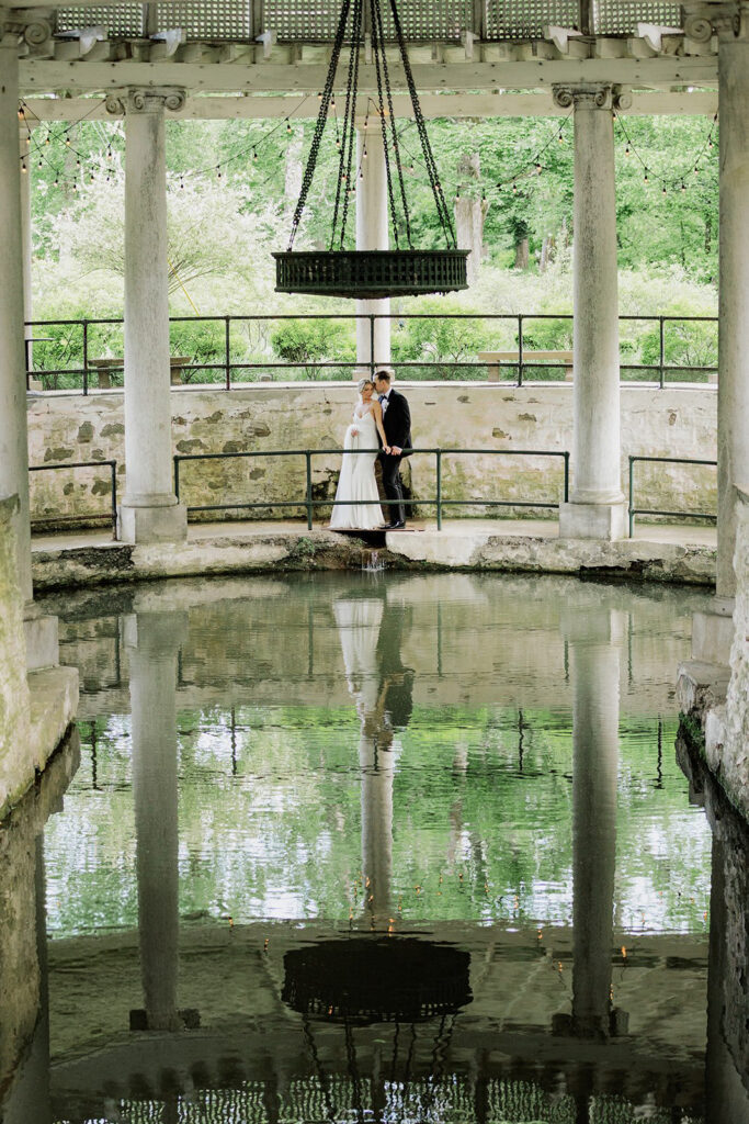 Castle & Key wedding couple standing beside the reflecting pool pavilion with their reflection mirrored in the water.