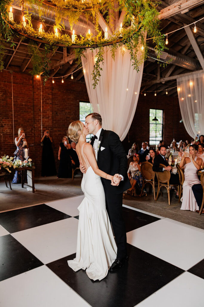 Castle & Key wedding couple sharing their first dance beneath a greenery chandelier and draped reception decor.