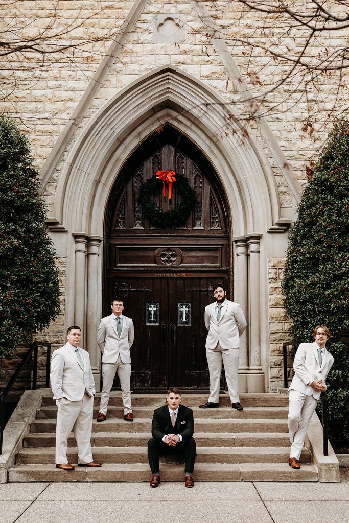 Groom and groomsmen posing on stone church steps outside the entrance in Louisville, KY.