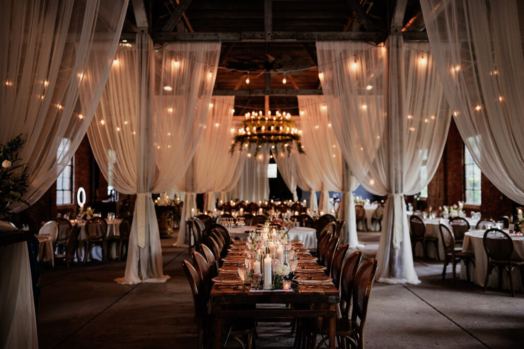 Shooking Building reception space with draped fabric, candlelit tables, and chandelier lighting.