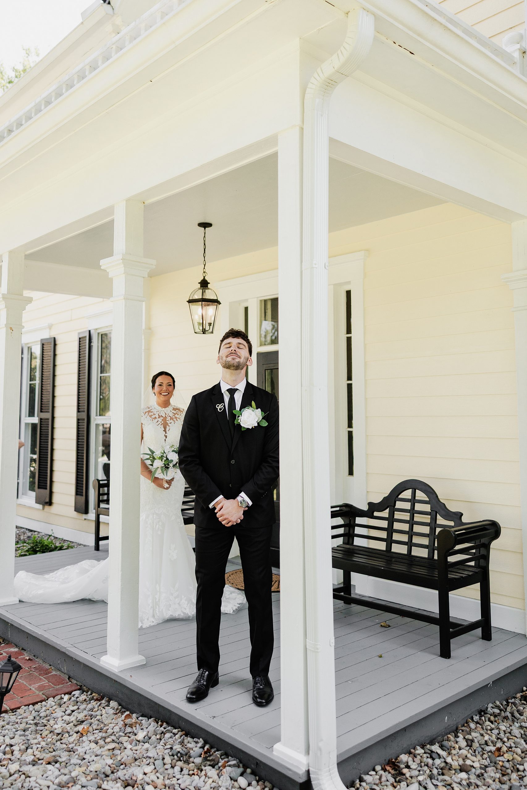 Groom waits on the porch as his bride approaches for their wedding first look.