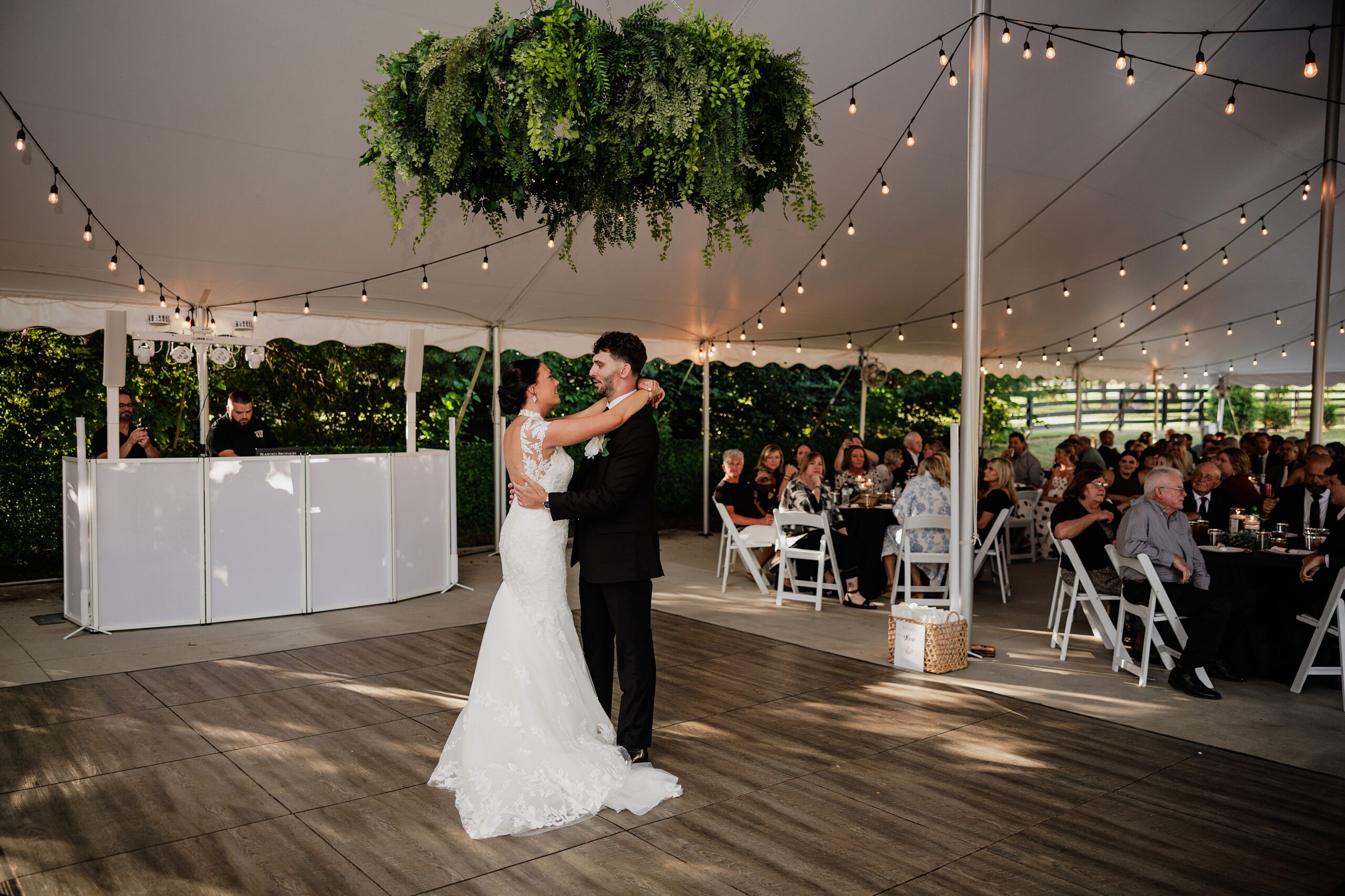 Newlyweds share their first dance as guests watch inside the tented wedding reception.
