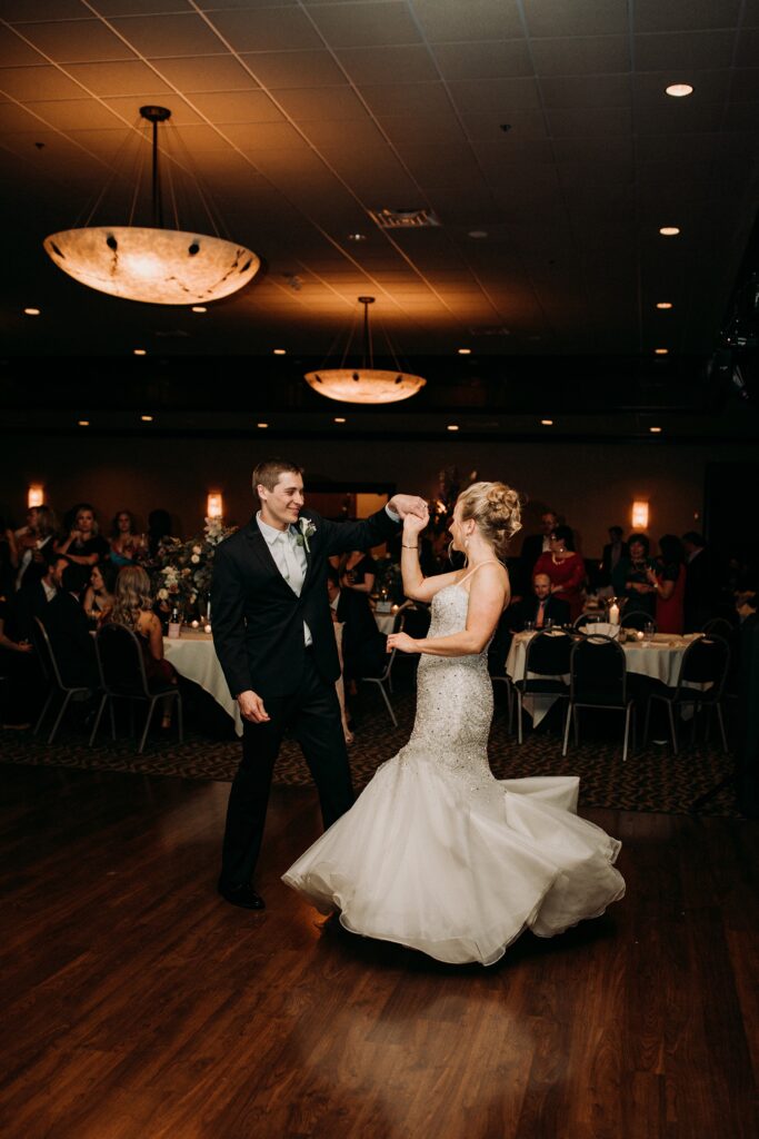 Groom twirls bride during their first dance in the Heritage reception room at Huber's winery 