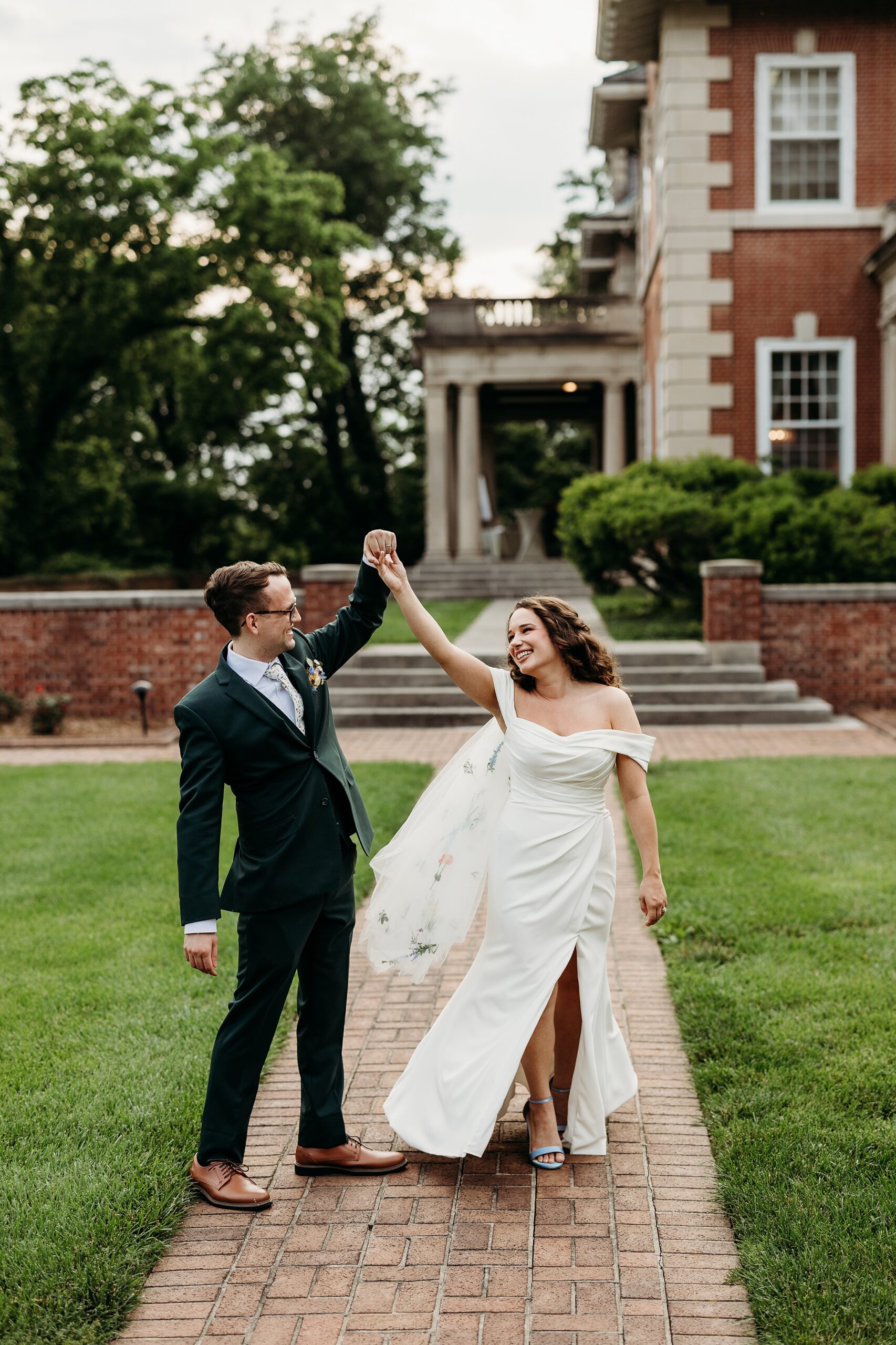 Groom twirls bride in front of Gardencourt on their wedding day.