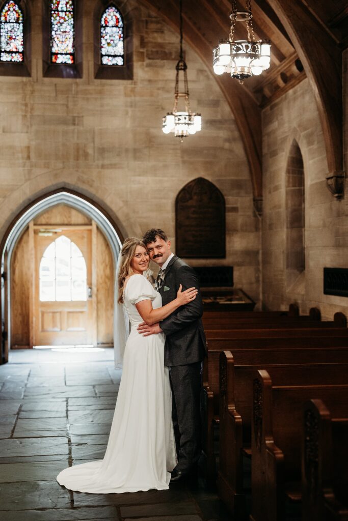 Bride and groom embrace in aisle at Duncan Memorial Chapel