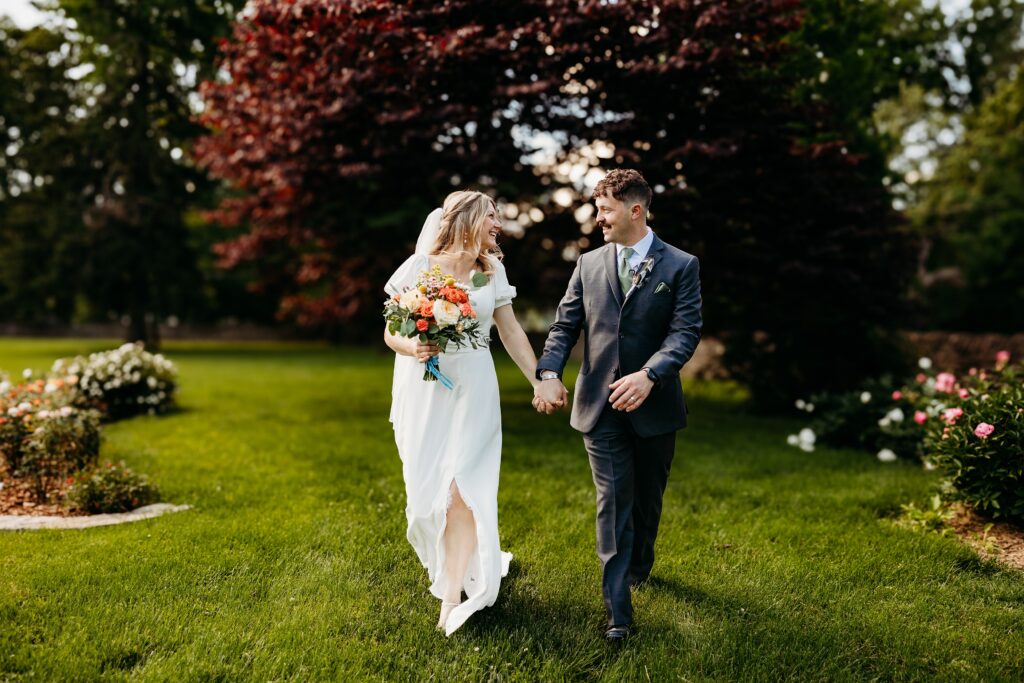 Couple walking hand in hand through a garden on their wedding day