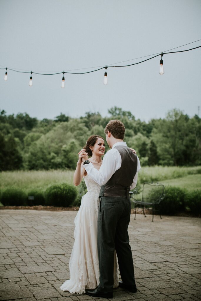 Yew Dell couple sharing their first dance on the outdoor patio beneath string lights at their wedding reception.