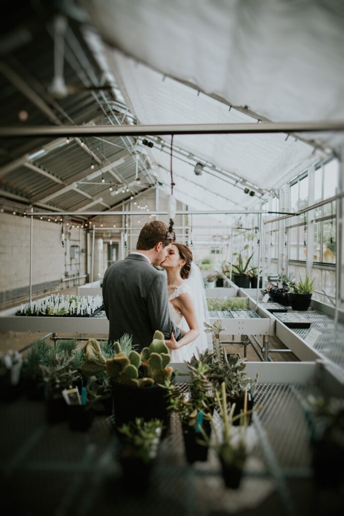 Yew Dell greenhouse wedding portrait of the bride and groom kissing among cactus and succulent displays.