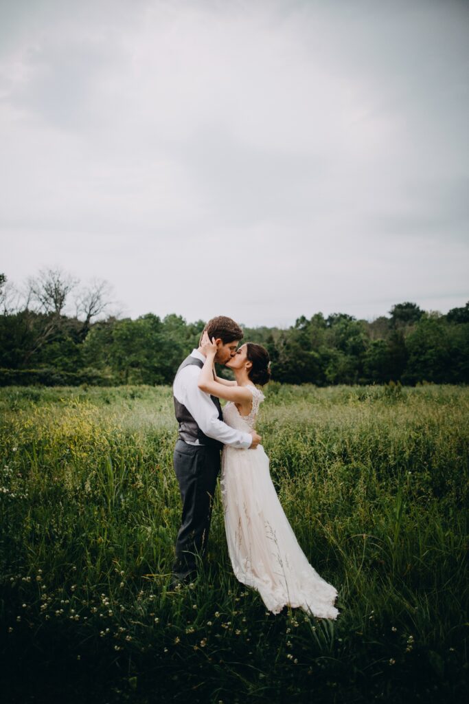 Yew Dell wedding portrait of the bride and groom kissing in a wildflower meadow at sunset.
