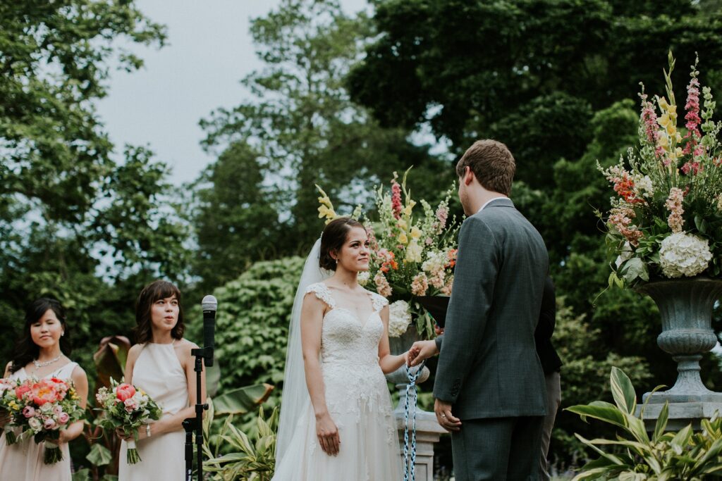 Yew Dell wedding ceremony on the Event Lawn with the couple exchanging vows surrounded by colorful floral arrangements.