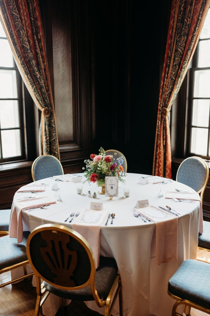 Garden Court reception table with elegant floral centerpiece, place settings, and wood paneled walls.