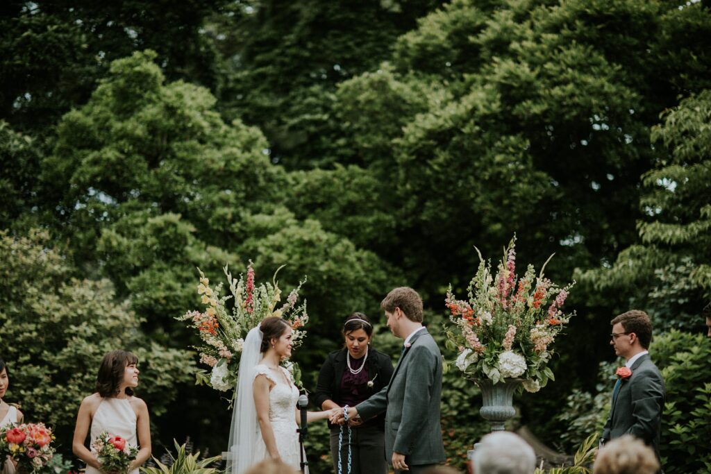 Yew Dell wedding ceremony on the Event Lawn as the couple exchanges vows beneath colorful floral arrangements surrounded by lush gardens.