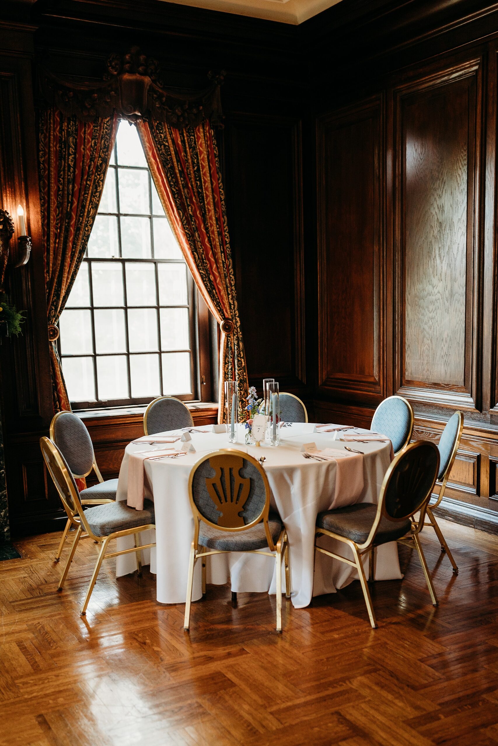 Garden Court reception room with rich wood paneling, elegant drapery, and a beautifully set wedding reception table.
