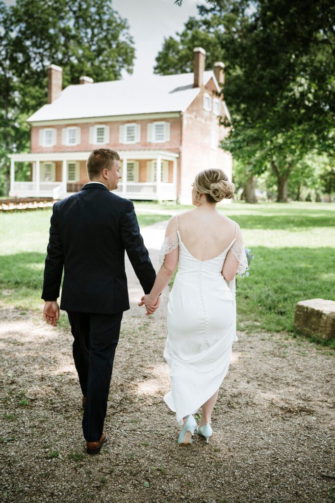 Bride & Groom walks hand in hand toward historic mansion in Louisville.