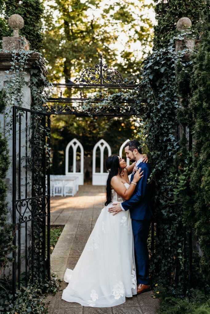 Bride and groom sharing a quiet moment beneath the ivy covered garden gate with the intimate ceremony site in the background.
