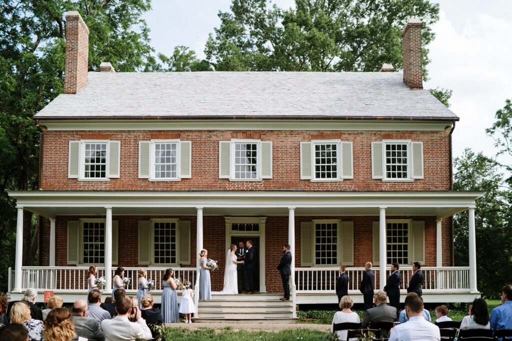 Small outdoor wedding ceremony on front porch of Louisville historic home with guests seated on the lawn.