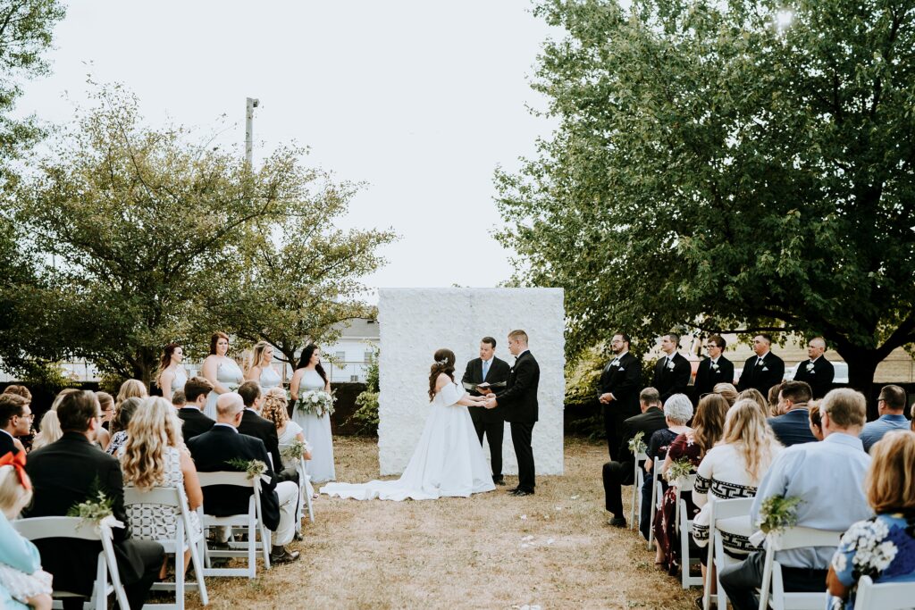 Outdoor ceremony with floral backdrop.
