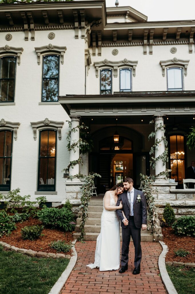 Bride and groom portrait in front of the historic mansion entrance and front porch
