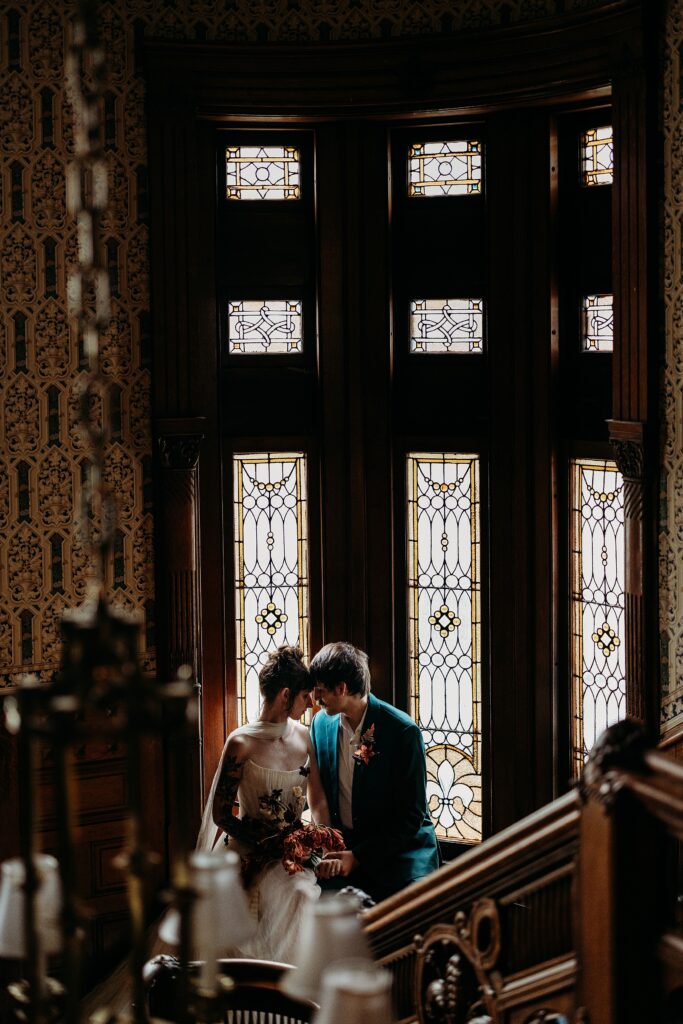 Couple embraces before stained glass windows inside historic home in Louisville.