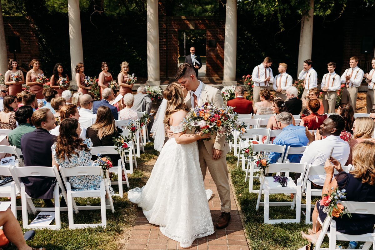Bride and groom kiss at gardencourt ceremony exit.