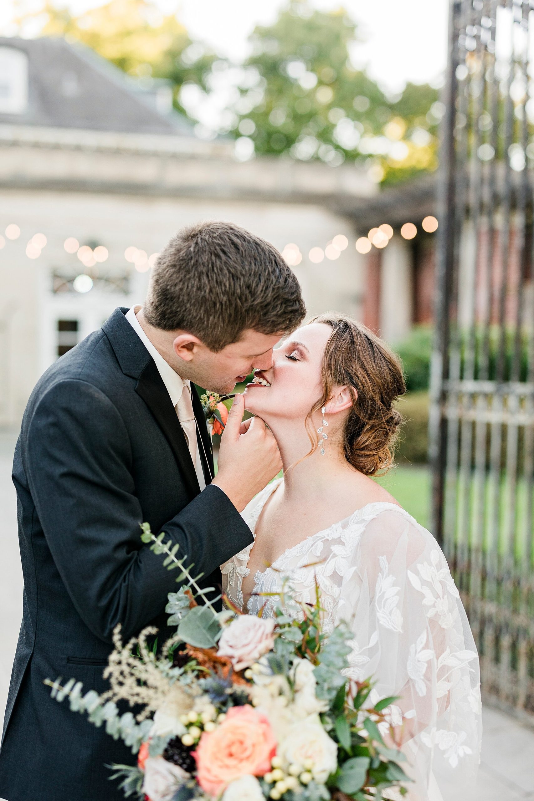 Bride and groom kiss in front of Gardencourt's iron gate in Louisville, KY