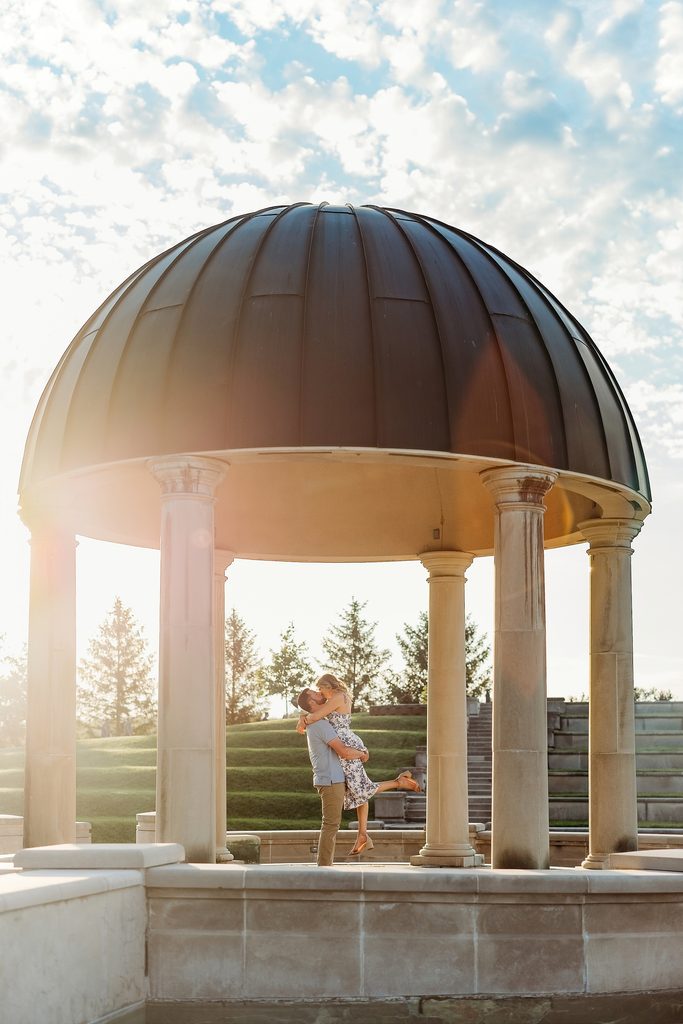 Couple kissing beneath the domed gazebo during their Coxhall Gardens engagement session.