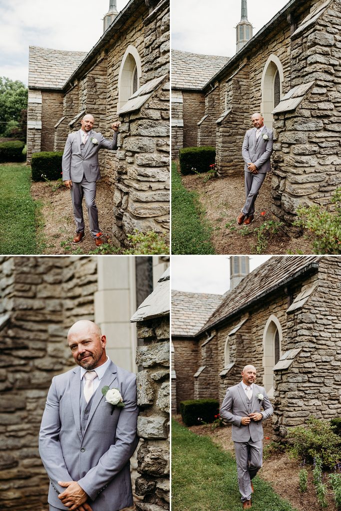 Groom in a gray three-piece suit posing beside the stone chapel exterior.