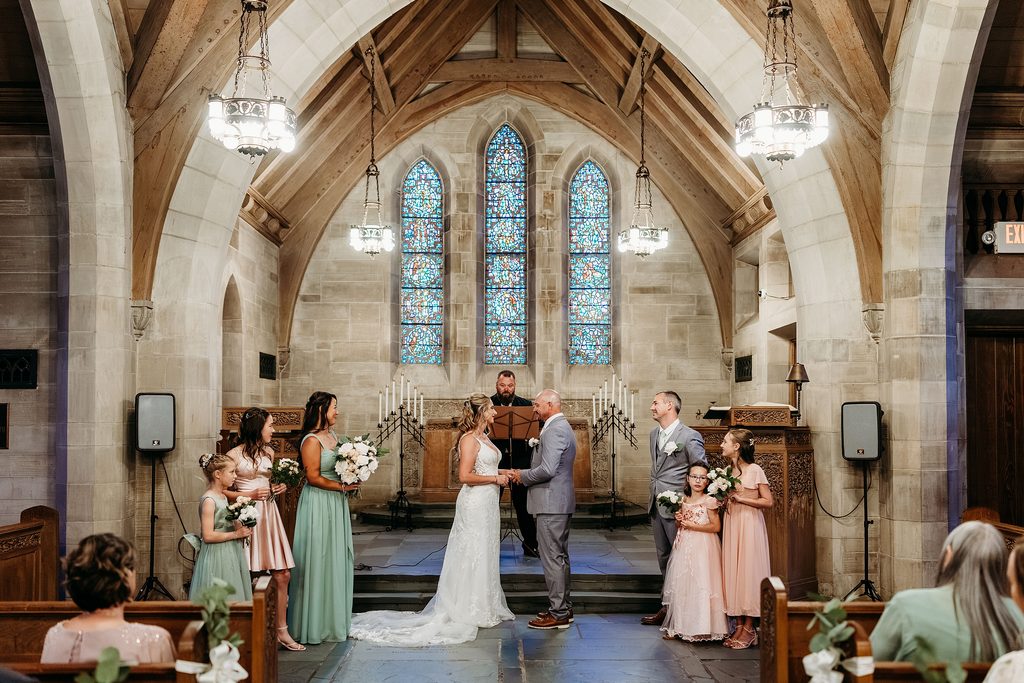 Bride and groom stand at the altar during their small chapel wedding ceremony.