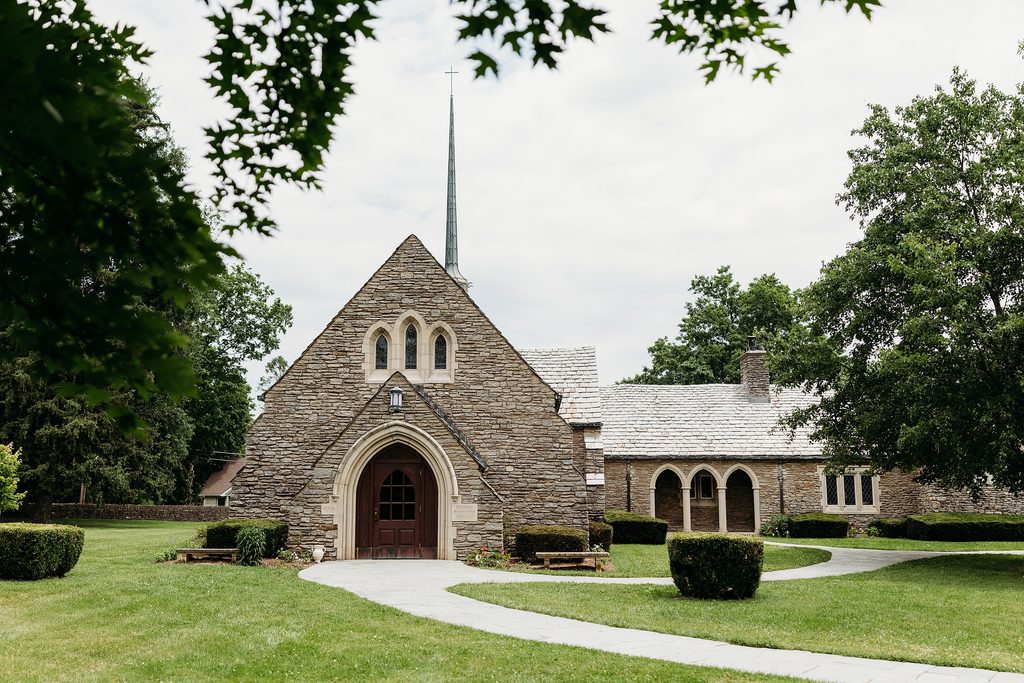 Historic stone chapel surrounded by green lawn and trees, ideal for an intimate chapel wedding.