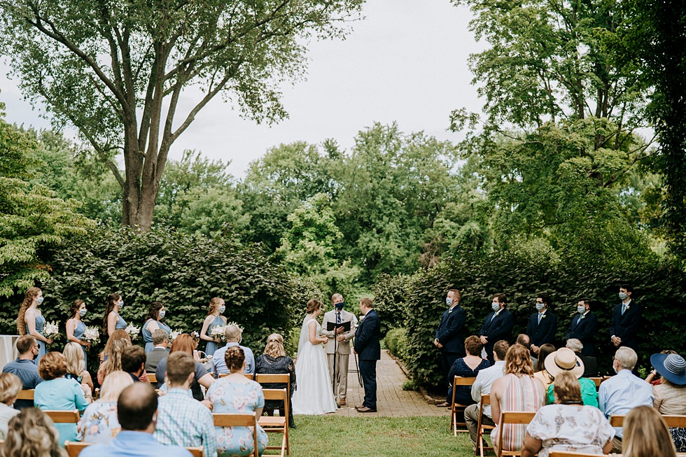 Couple exchanges vows during an outdoor garden wedding ceremony at Farmington surrounded by family and friends.
